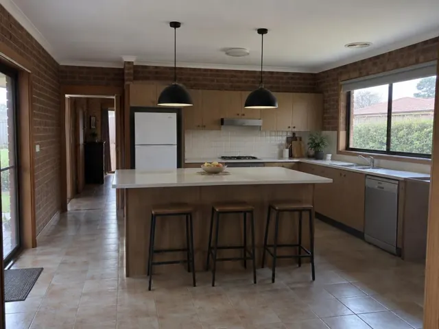 Kitchen with two black pendant lights over an island in a brick home in Chisholm